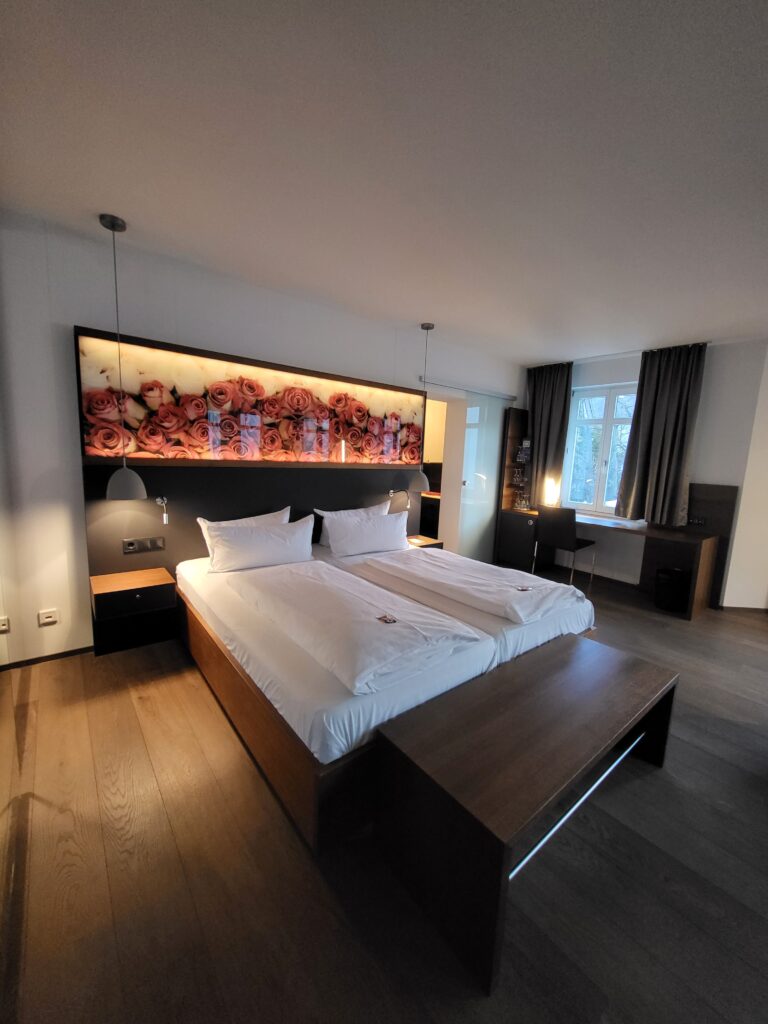 Doppelbett in beleuchtetem Zimmer mit Rosenbild