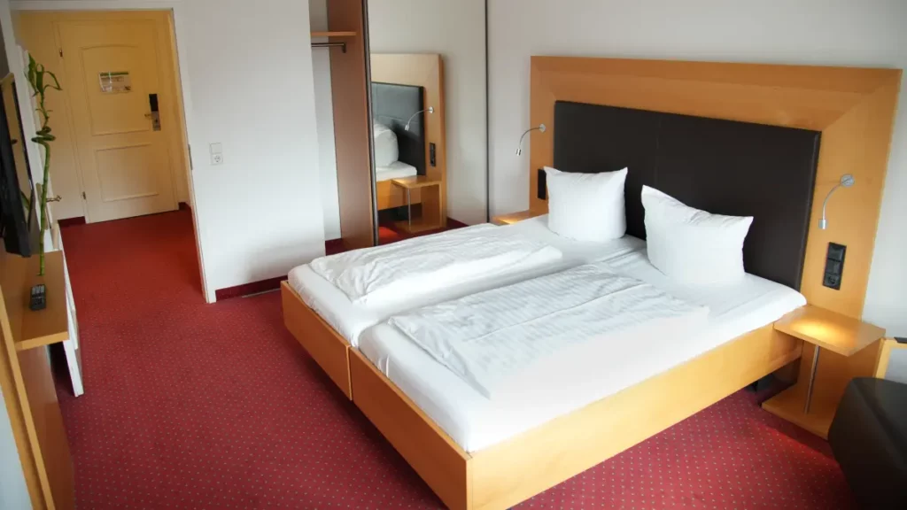 Doppelbett mit Spiegelschrank und rotem Teppichboden