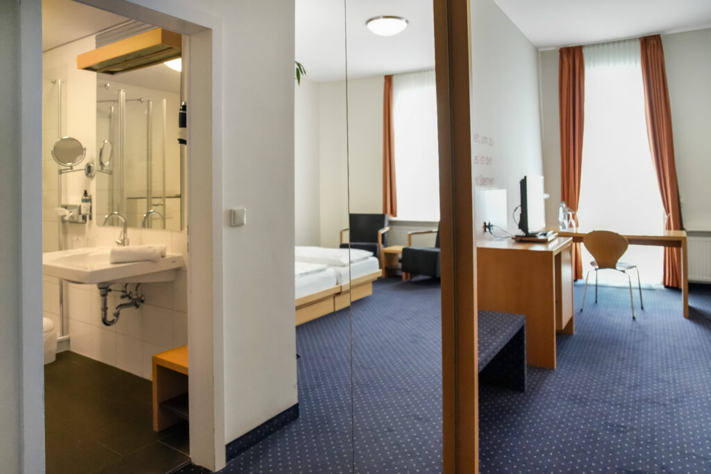 Blick auf Zimmer mit Spiegelschrank, Bad und Doppelbett