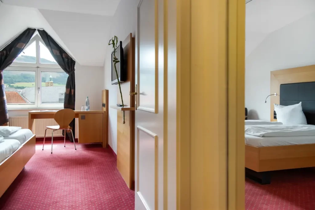 Blick in ein Zimmer mit Doppelbett und Spiegelschrank