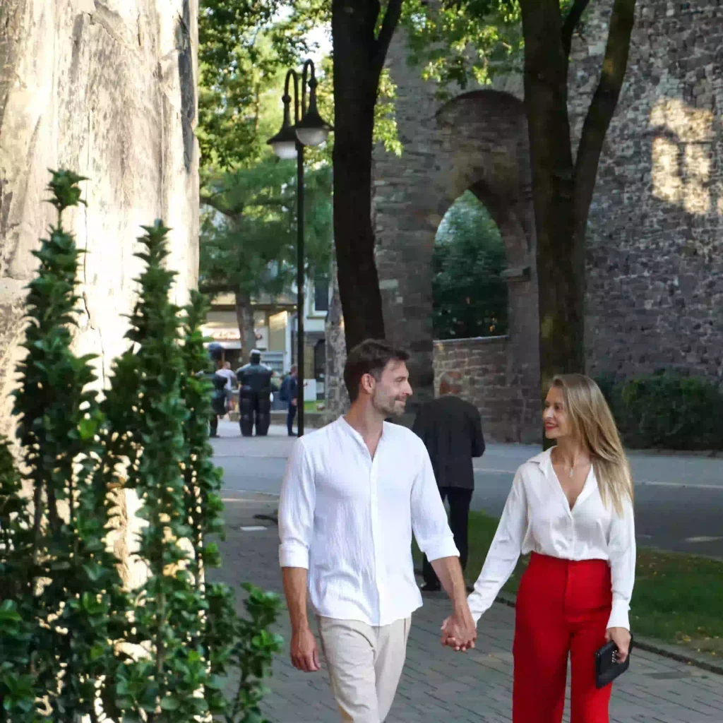 Paar spaziert Hand in Hand durch grünen Innenhof des Hotels