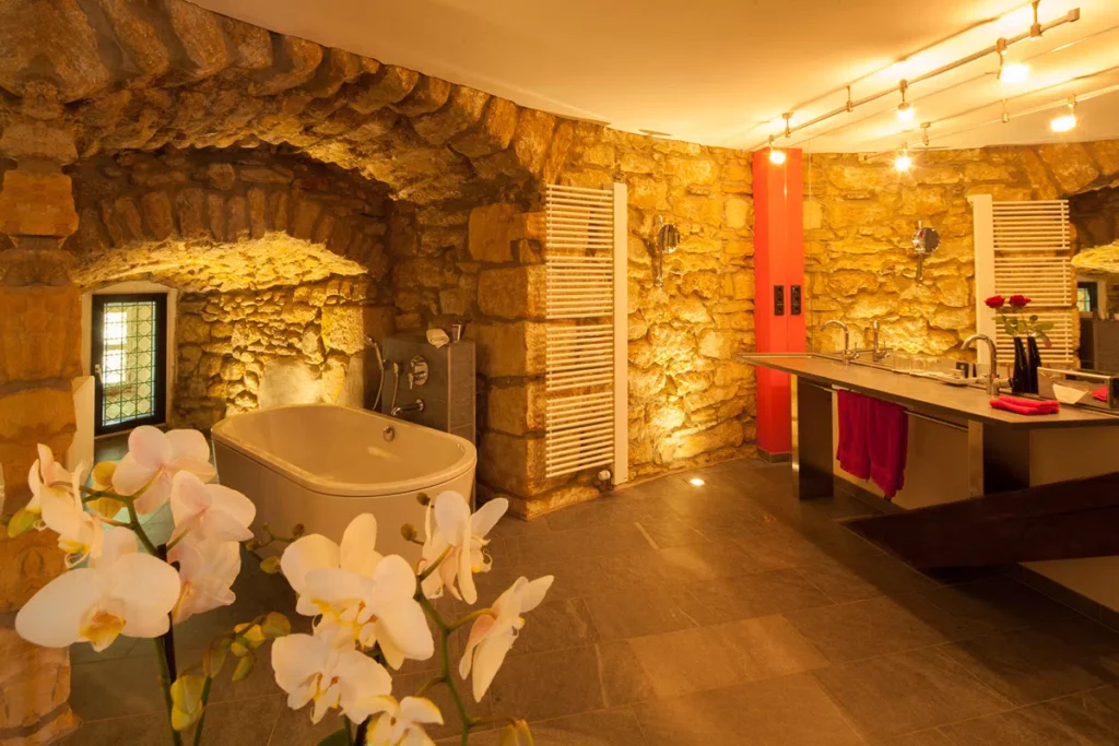 Historisches Badezimmer mit Steinwänden, moderner Wanne und Waschbecken