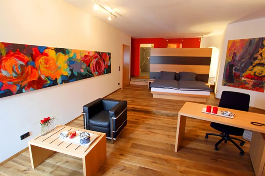 Modern eingerichtetes Hotelzimmer mit Doppelbett und farbigen Bildern
