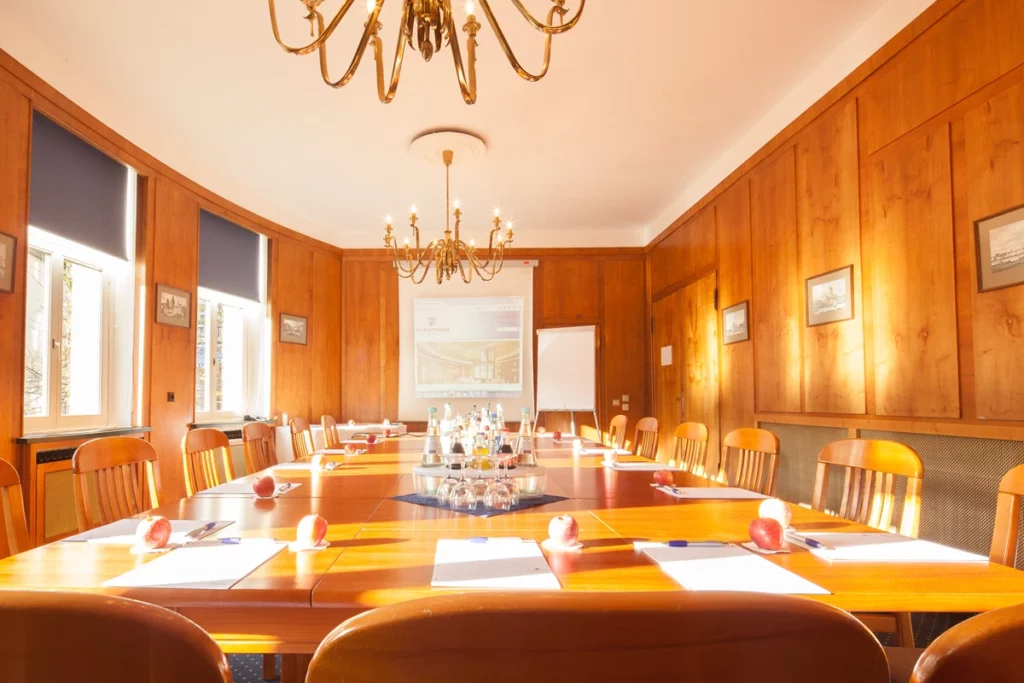 Holzgetäfelter Konferenzraum mit Wasserflaschen und Blocktischen