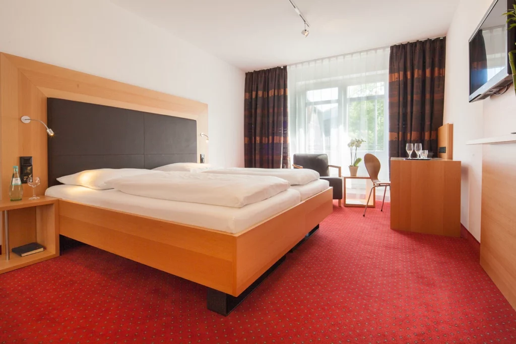 Doppelbettzimmer mit Gardinen und rotem Teppichboden