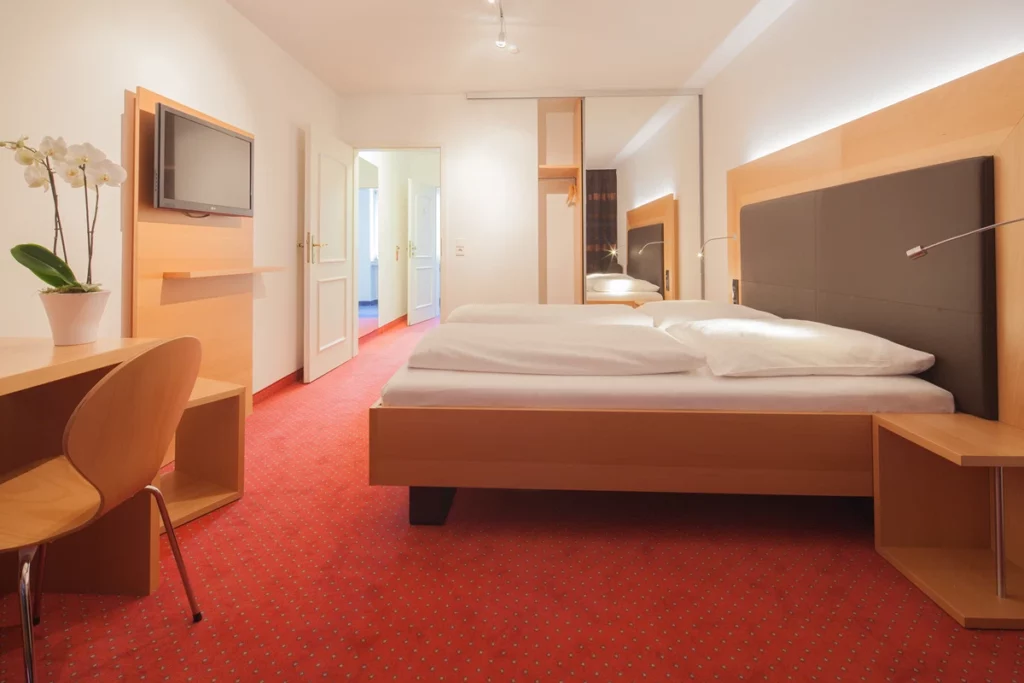 Zimmer mit rotem Teppichboden und Doppelbett